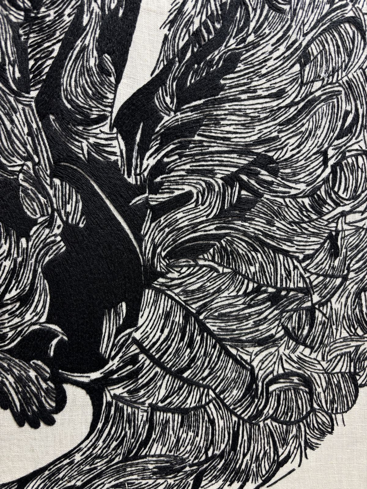 Close detail of black-thread stitching, radiating feather forms